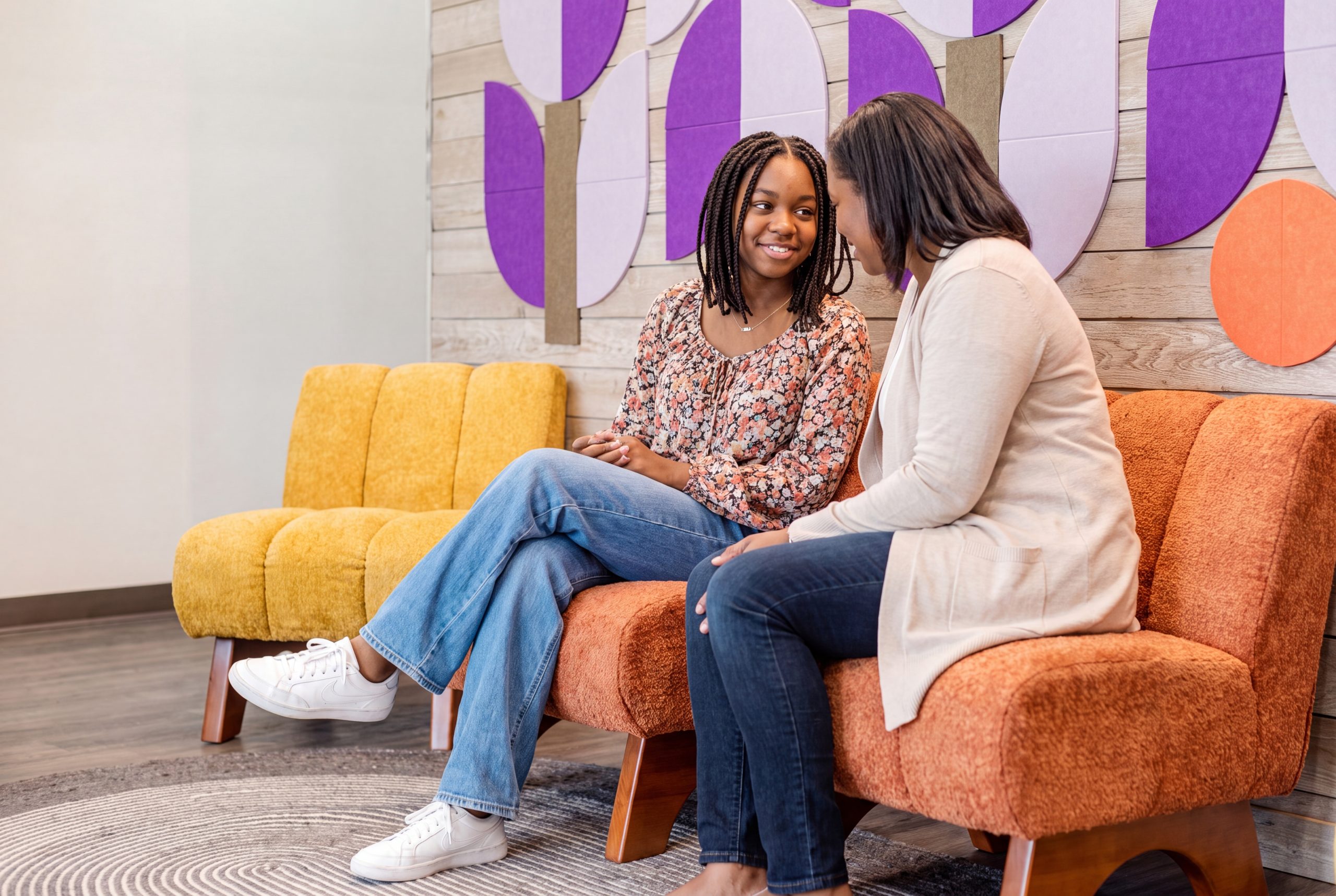 black teen girl and her mother sitting on couch at Avery's House