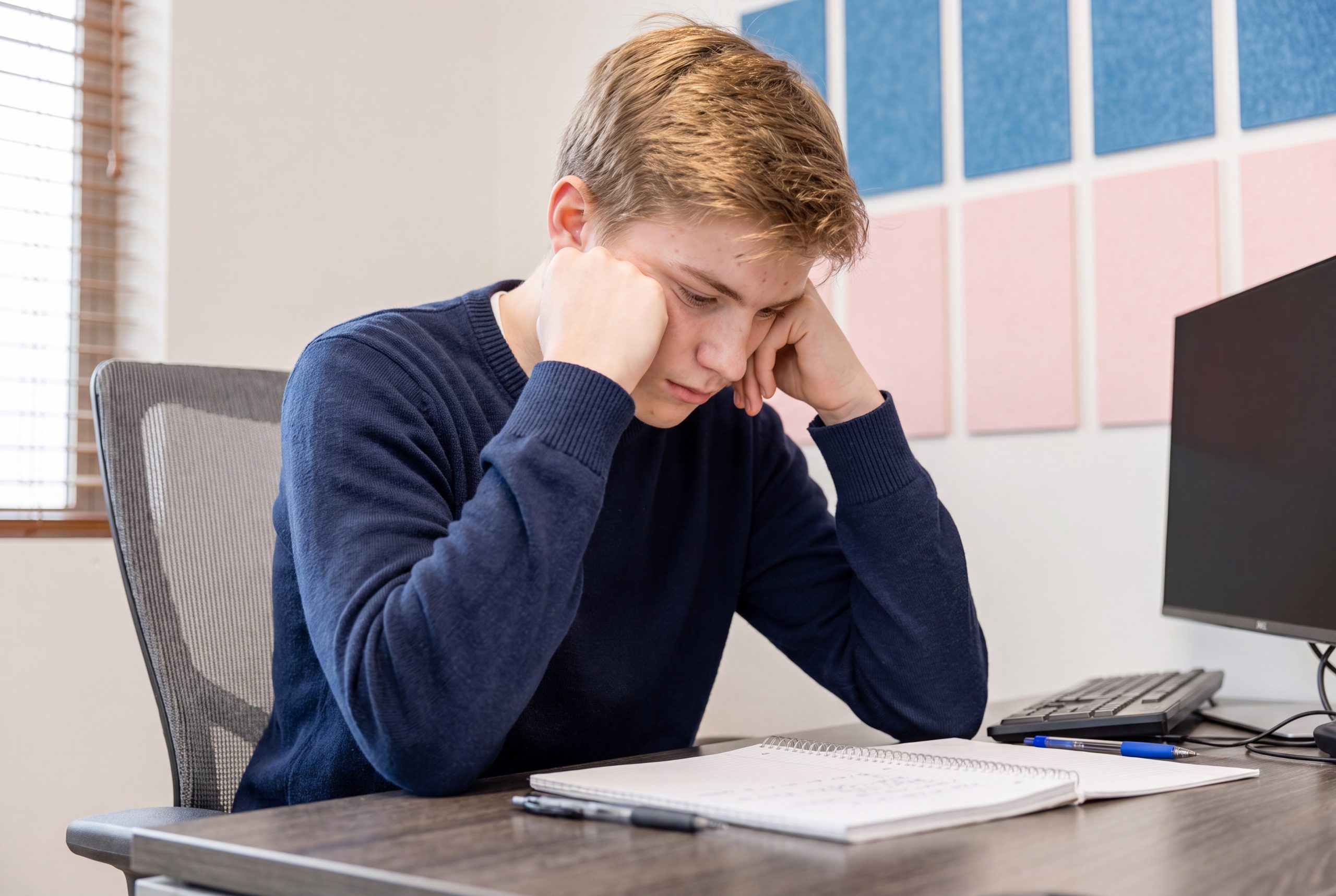 teen boy looking sad at desk